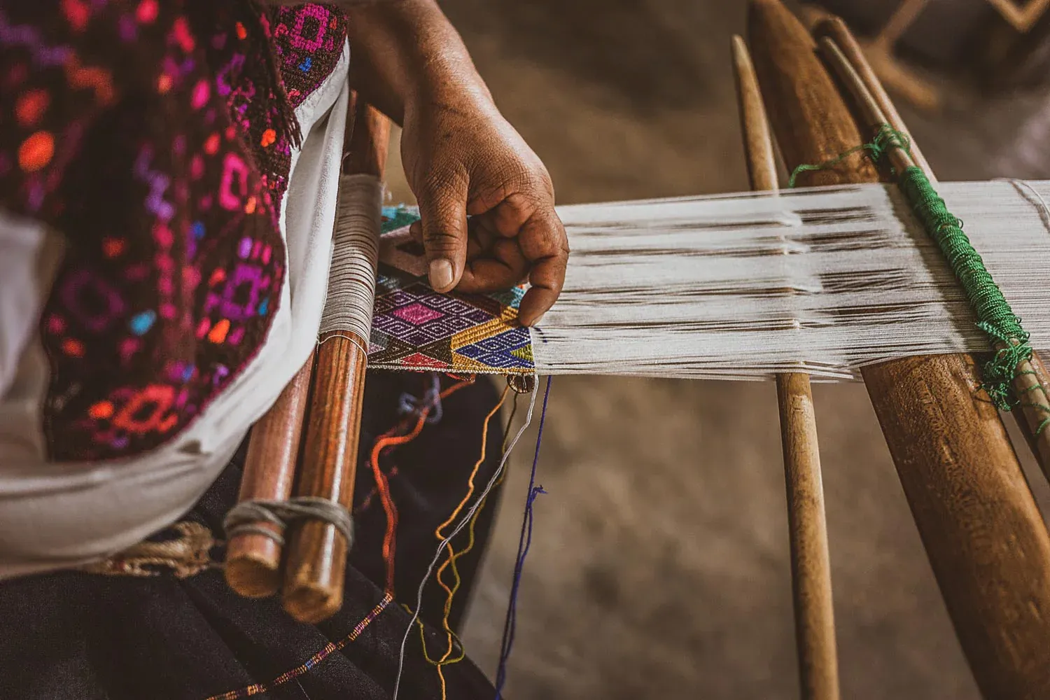 Close-up of an artisan's hands weaving on a traditional loom
