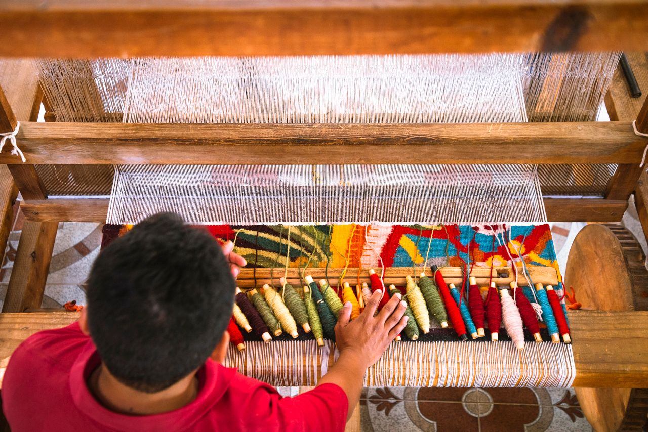 Colorful thread spools being set up on a traditional loom